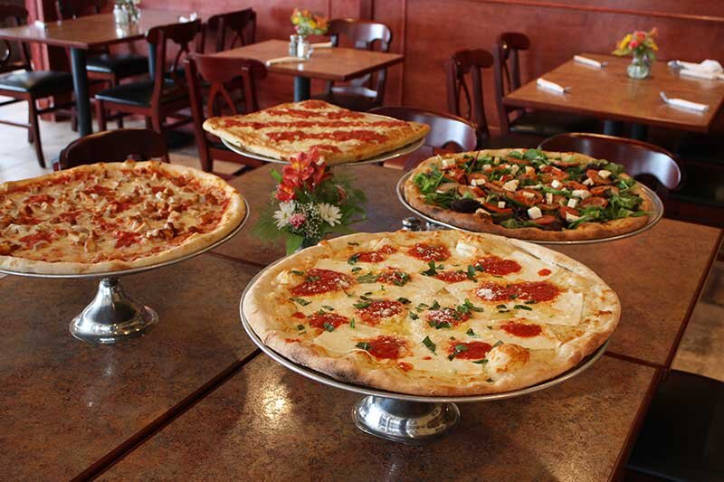 Multiple pizzas on a platters placed on a table