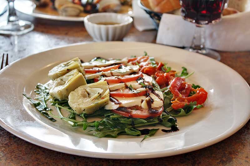 Fresh mozzarella, tomato, artichoke heart and peppers on a bed of arugula